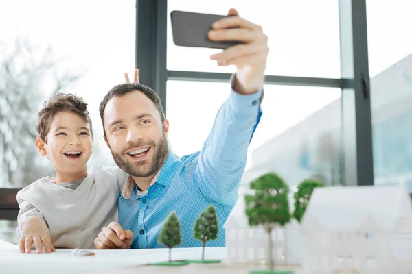 Feliz padre e hijo tomando selfie en la oficina —  Fotos de Stock