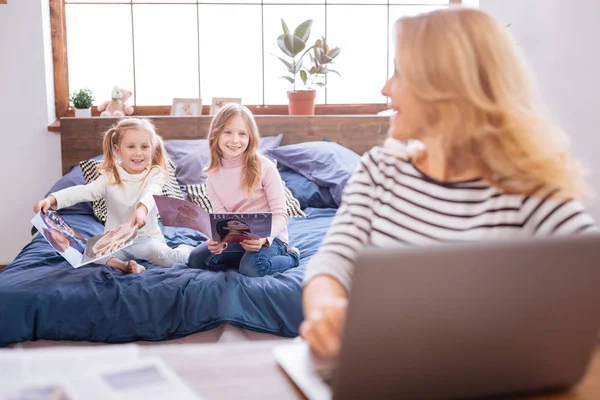 Joyful little sisters reading magazines