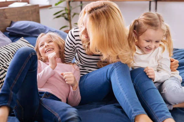 Улыбающаяся мама играет со своими детьми на диване — стоковое фото