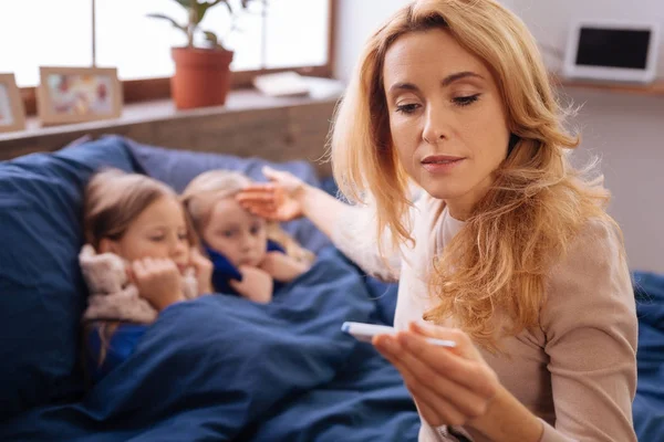 Madre con problemas para tomar la temperatura de sus hijos — Foto de Stock