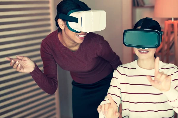 Dos mujeres jóvenes jugando con auriculares VR y riendo —  Fotos de Stock