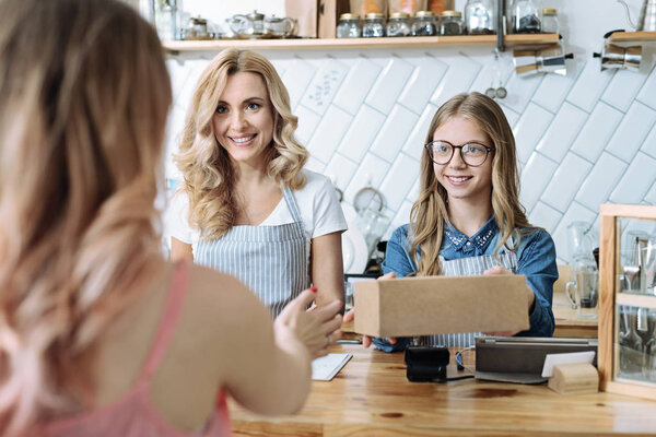 Attractive girl taking craft box to client