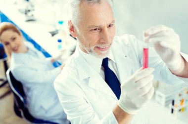 Memnun araştırmacı test tüpü sıvı ile bakarken gülümseyen