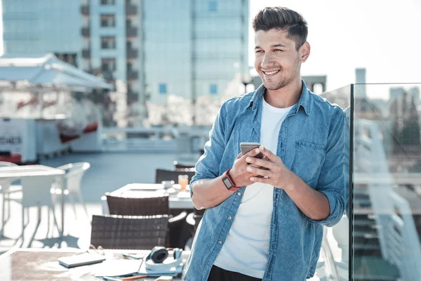 Красивый молодой человек, использующий смартфон на террасе — стоковое фото