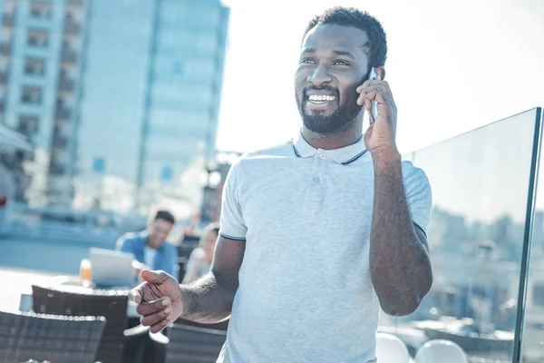 Radiant young man enjoying phone conversation