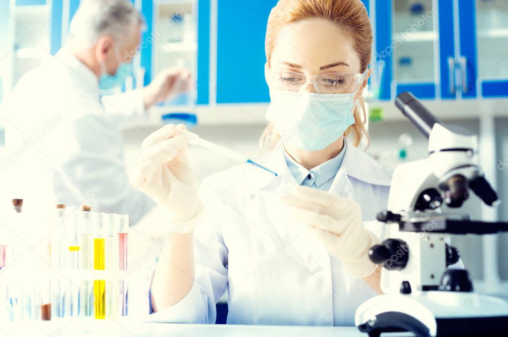 Female researcher taking sample of chemical liquid