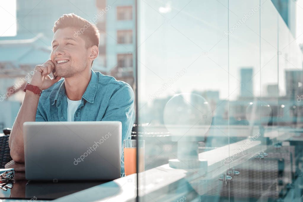 Happy young man enjoying phone conversation outdoors
