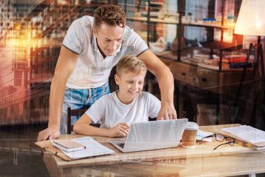 Özenli baba oğlu ev ödevlerinde yardımcı olurken ekrana işaret