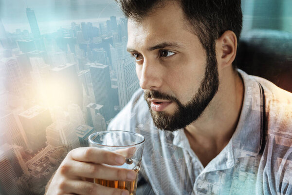 Thoughtful man looking into the distance while drinking alcohol