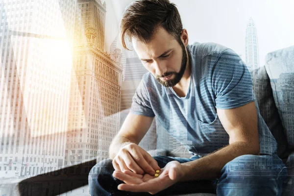 Upset bearded man eating pills — Stock Photo, Image