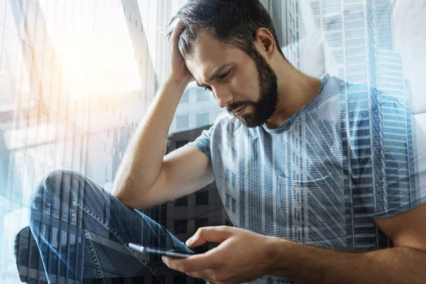 Stanco maschio barbuto utilizzando il suo gadget — Foto Stock