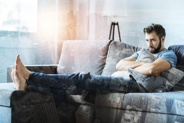 Sad thoughtful man lying on the sofa and looking aside. — Stock Photo, Image