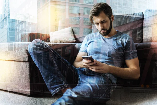 Young man reading messages while sitting on the floor — Stock Photo, Image