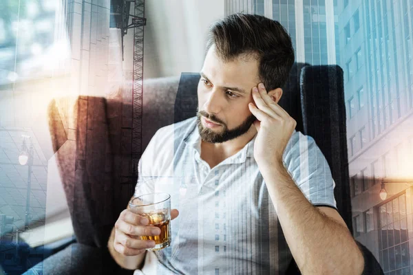 Moe jonge man zitten in zijn leunstoel en drinken van alcohol — Stockfoto