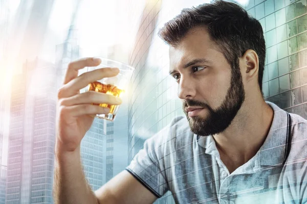 Вдумчивый мужчина сидит и смотрит на алкоголь в стакане — стоковое фото