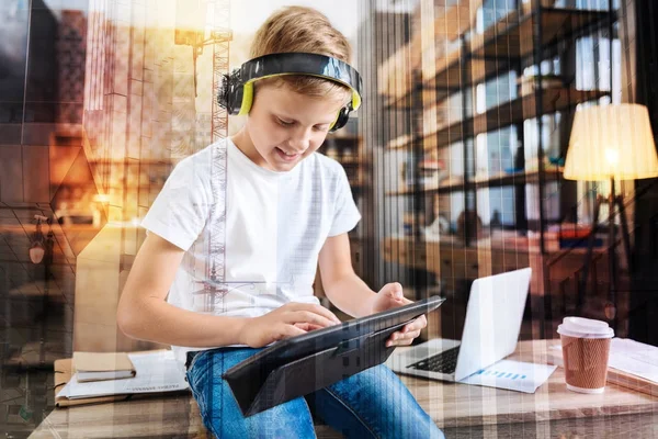 Ragazzo allegro che gioca con il suo nuovo tablet e ascolta musica — Foto Stock