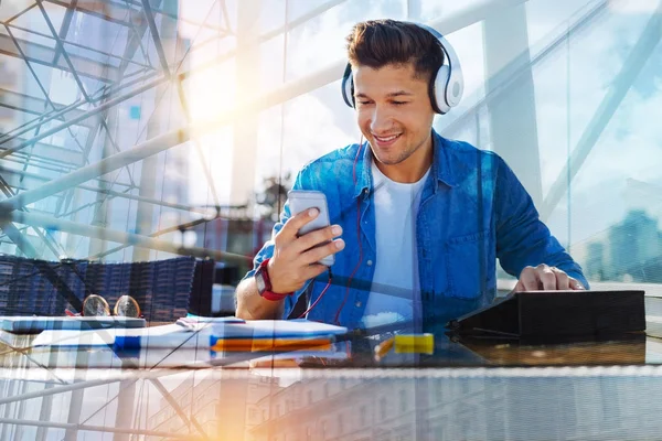 Lycklig man bär hörlurar och håller en telefon — Stockfoto