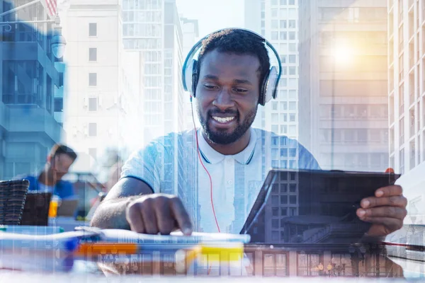 Lächelnder afroamerikanischer Mann, der während der Arbeit Musik hört — Stockfoto
