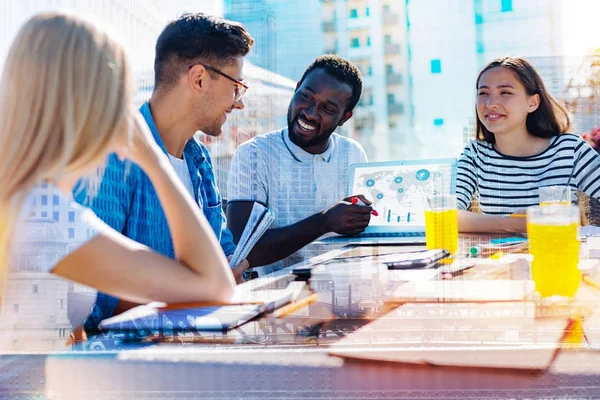 Feliz hombre afroamericano discutiendo trabajo con sus compañeros de trabajo —  Fotos de Stock