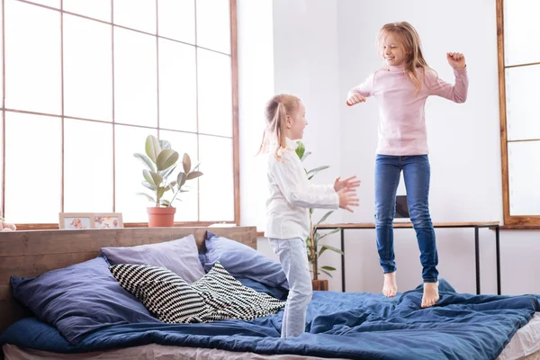Leende flickor hoppar på sängen — Stockfoto