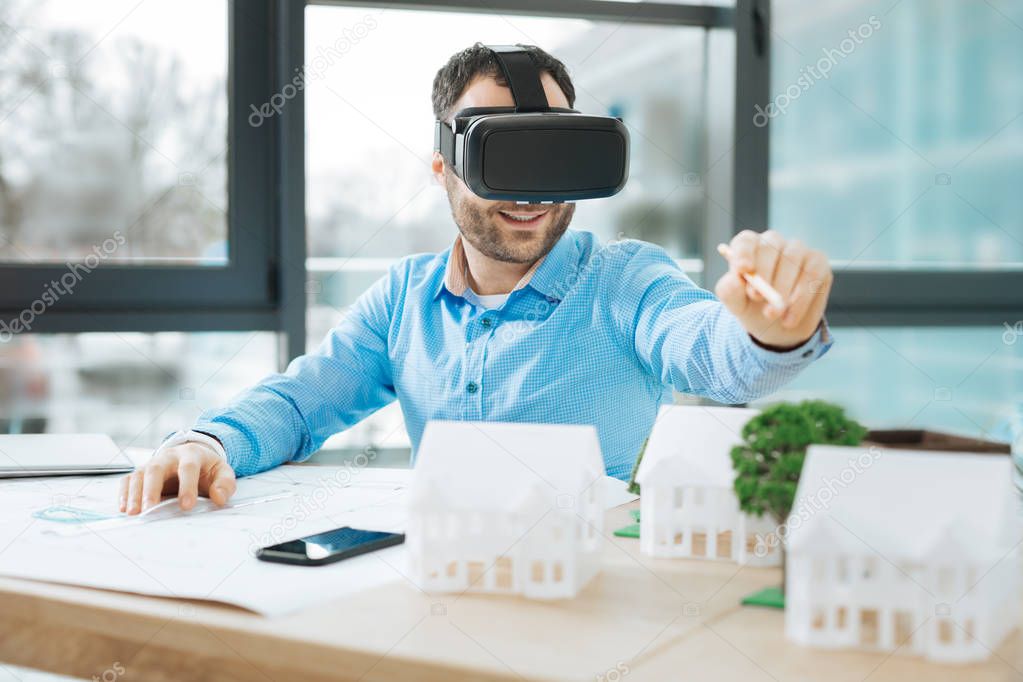 Smiling engineer using VR headset while designing construction