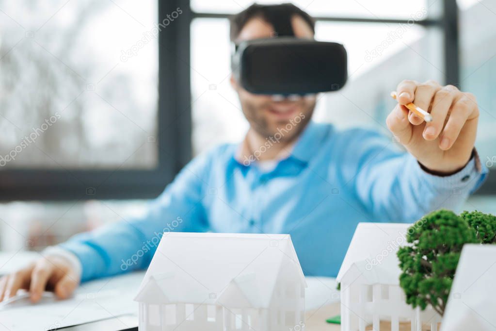 Young engineer in VR headset pointing at models