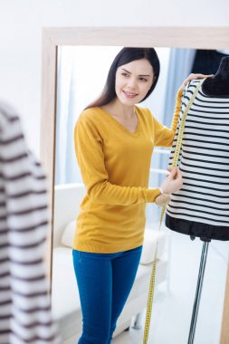 Gülümseyen ve uzunluğu bir aynaya bakarak sorumlu terzi