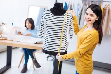 Bir manken ve bir mezura ile ayakta ve gülümseyen mutlu terzi