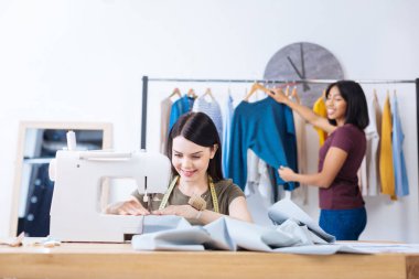 Onun iş arkadaşı onun arkasından ayakta iken dikiş yetenekli genç kadın