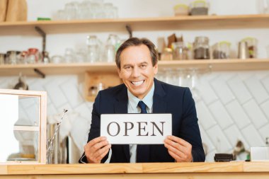 Neşeli gülümseyen adam bara ayakta ve plaka gösterilen.