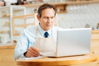 Dizüstü bilgisayar kullanarak ve bildirimleri yapma ciddi işgal altındaki adam.