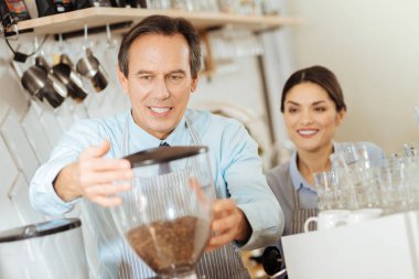 Ayakta ve kahve makinesi tutan konsantre ciddi adam.