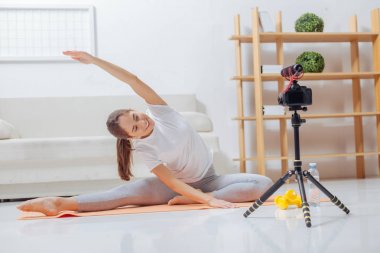 Bir yoga mat egzersizleri yaparken kameraya gülümseyen genç eğitmeni