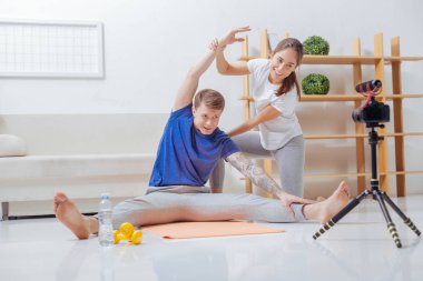 Neşeli eğitmen eşi üzerinde egzersiz gösteren