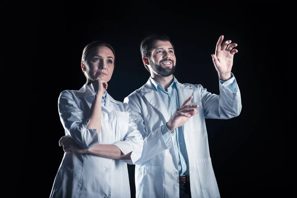 Nette nachdenkliche Frau, die neben ihrem Kollegen steht — Stockfoto