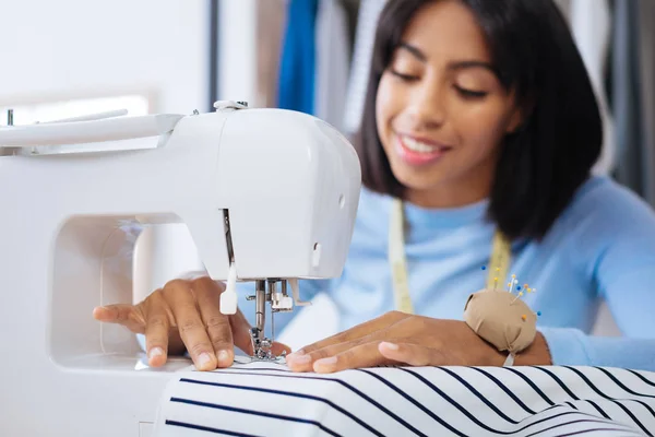 Alegre sastre haciendo puntadas con la ayuda de una máquina de coser —  Fotos de Stock