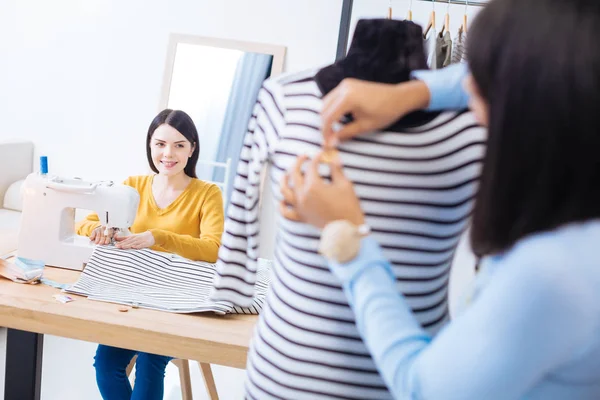 Cortés sastre sonriendo a su colega mientras se sienta y cose — Foto de Stock