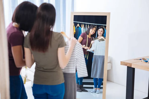 Cheerful women looking at their reflection in the mirror and smiling