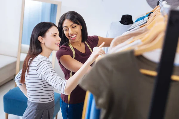 Emotionele kleermaker kijken naar de client terwijl het kiezen van kleding met haar — Stockfoto