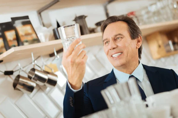 Pleasant joyful man smiling and overlooking a glass. — Stock Photo, Image