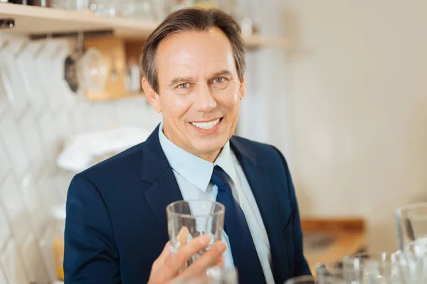 Sonriente hombre satisfecho de pie y sosteniendo un vaso . — Foto de Stock