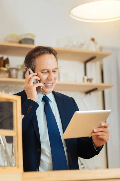 Ocupado hombre ocupado mirando la tableta y sosteniendo el teléfono celular . — Foto de Stock