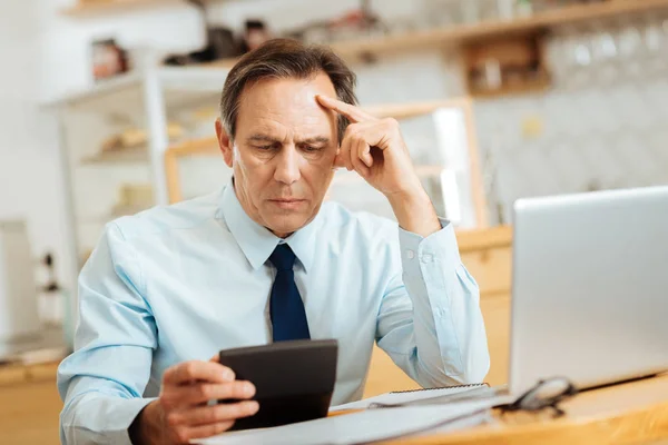 Senior konzentriert Mann sitzt und schaut auf den Taschenrechner. — Stockfoto