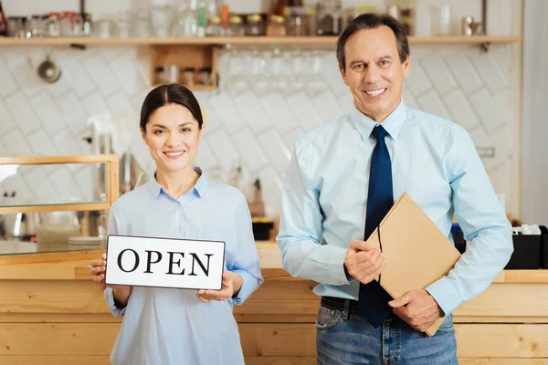 Hübsche junge Frau lächelt und zeigt den Teller. — Stockfoto