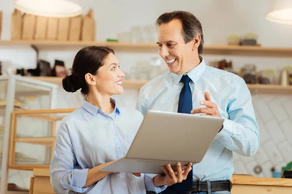 Tevreden collega's grappige met behulp van de laptop en glimlachen. — Stockfoto