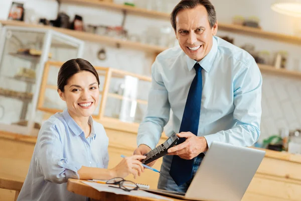 Tevreden prettige collega's met behulp van de calculator en glimlachen. — Stockfoto