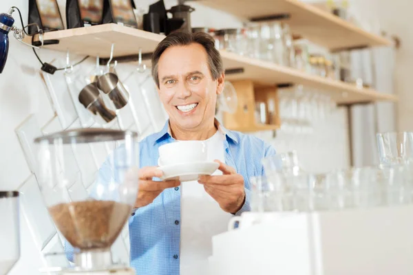 Satisfied joyful man smiling and giving a cup. — Stock Photo, Image