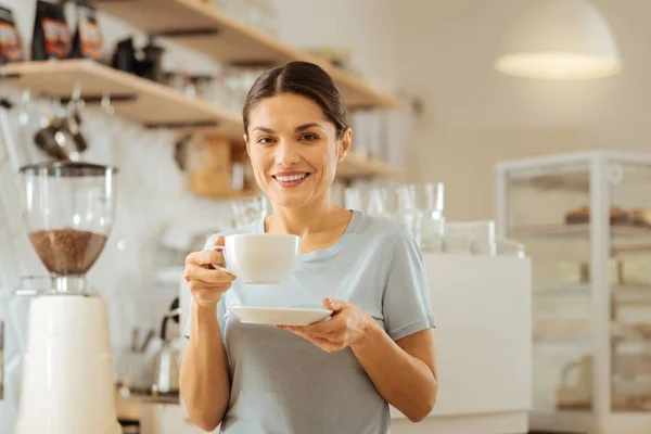 かなりうれしそうな女性は立ってコーヒーを飲む. — ストック写真