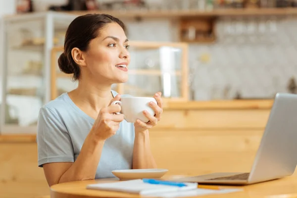 Радостная красивая женщина пьет кофе и смотрит в сторону . — стоковое фото
