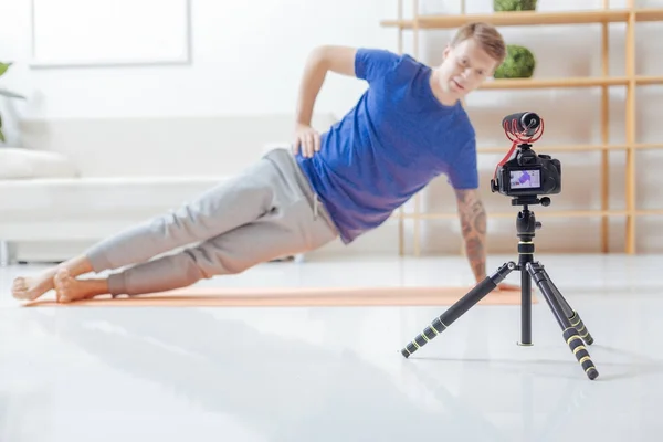 Blogueiro de vídeo concentrado fazendo exercícios ao olhar para a câmera — Fotografia de Stock